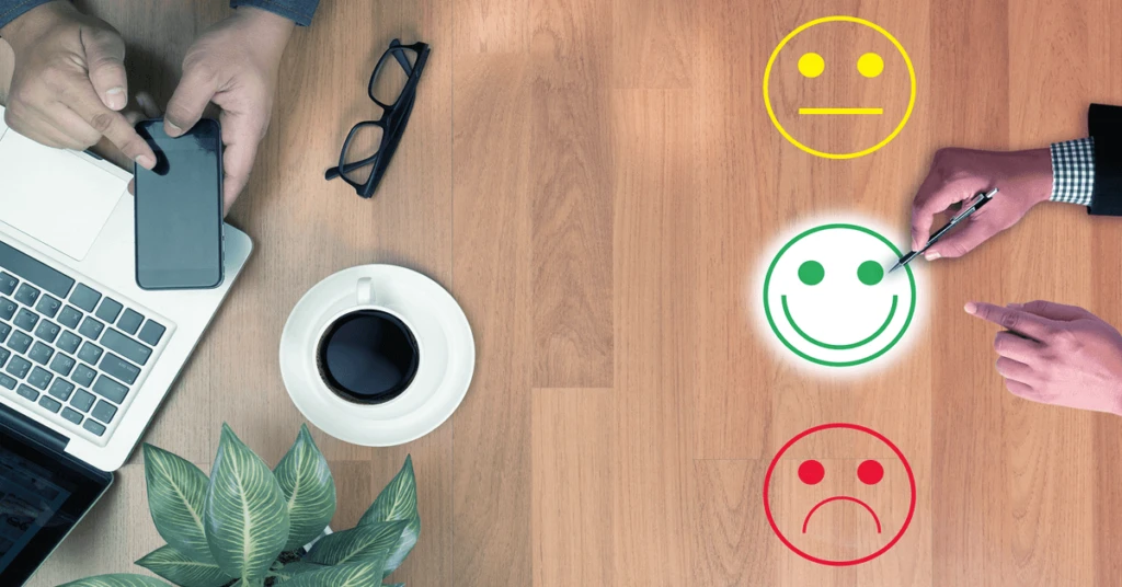 Imagem de avalia&ccedil;&atilde;o de satisfa&ccedil;&atilde;o no ambiente de trabalho, com s&iacute;mbolos de sorriso, neutro e tristeza, representando diferentes n&iacute;veis de feedback.